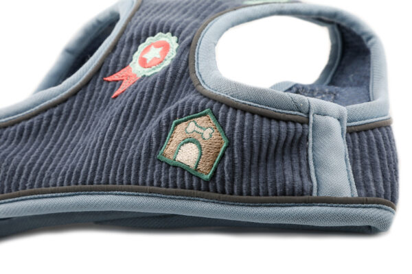 Front view of blue cord dog harness with embroidered dog-themed patches and brushed nickel hardware