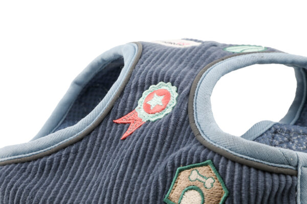 Front view of blue cord dog harness with embroidered dog-themed patches and brushed nickel hardware